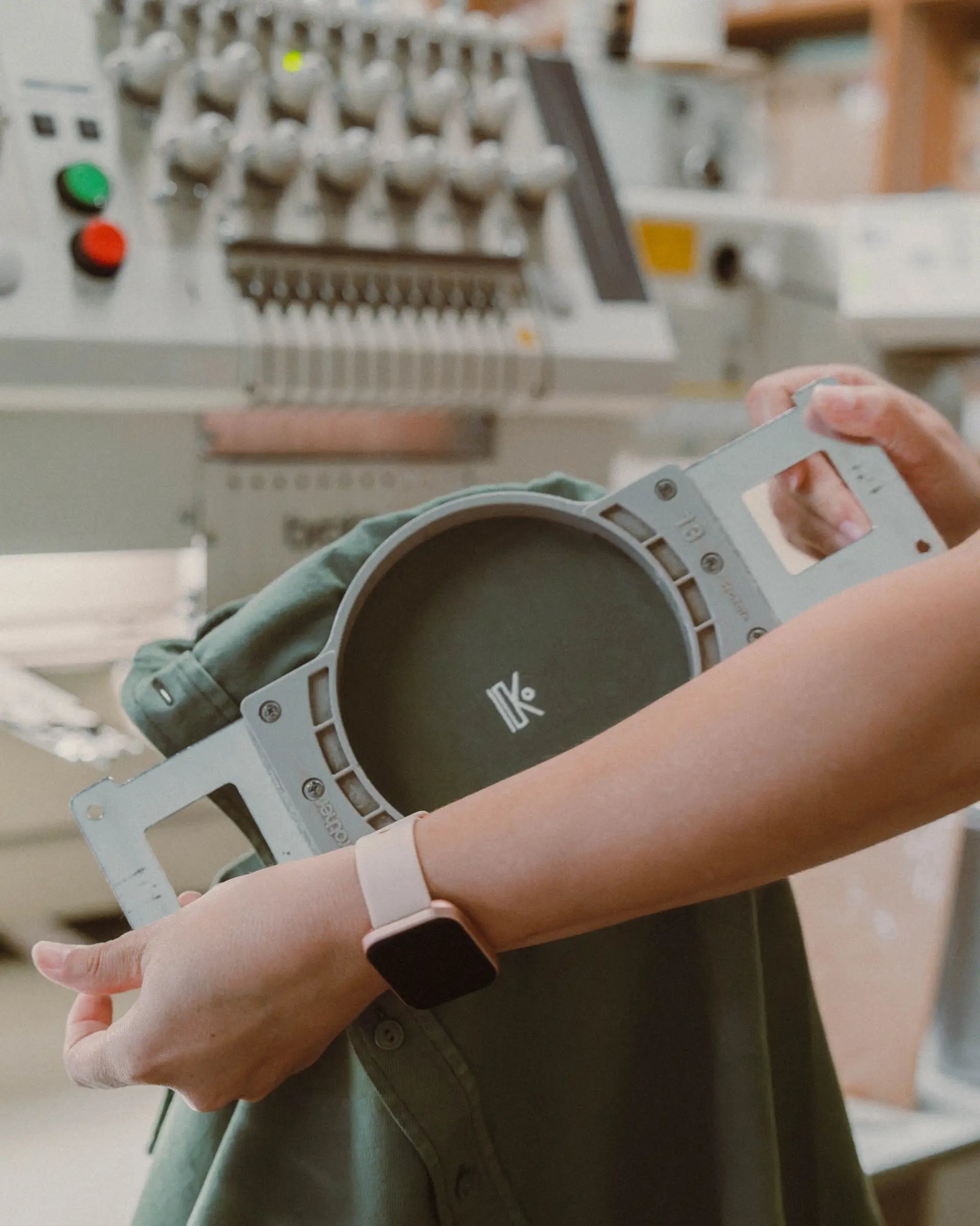 Broderie du logo K sur un vêtement vert, machine à broder de l'atelier au Pays basque